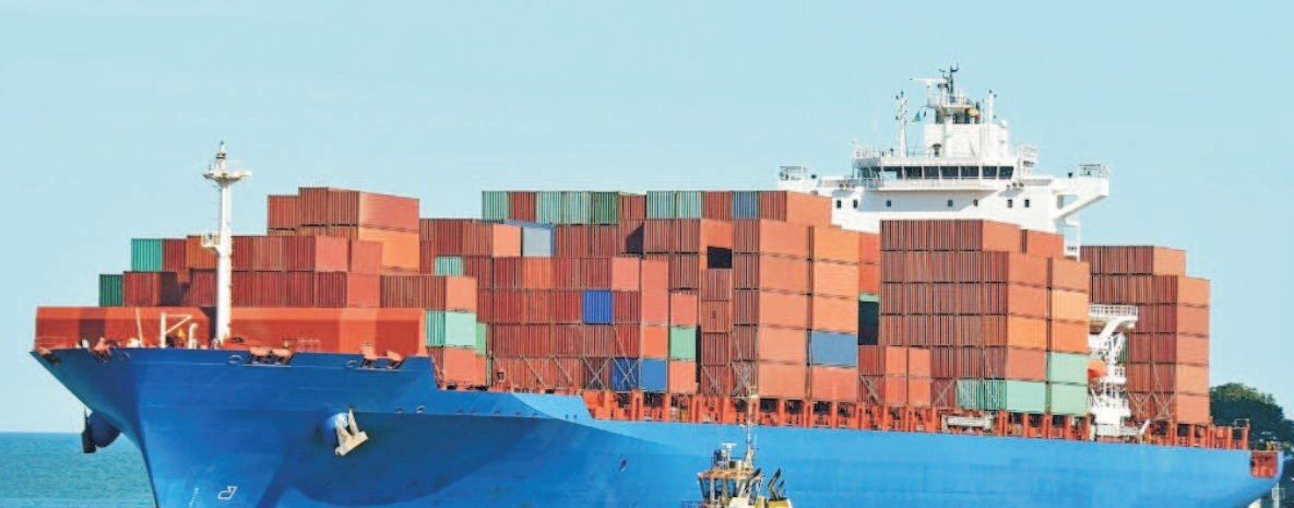 A container ship docked at a port with cranes in the background
